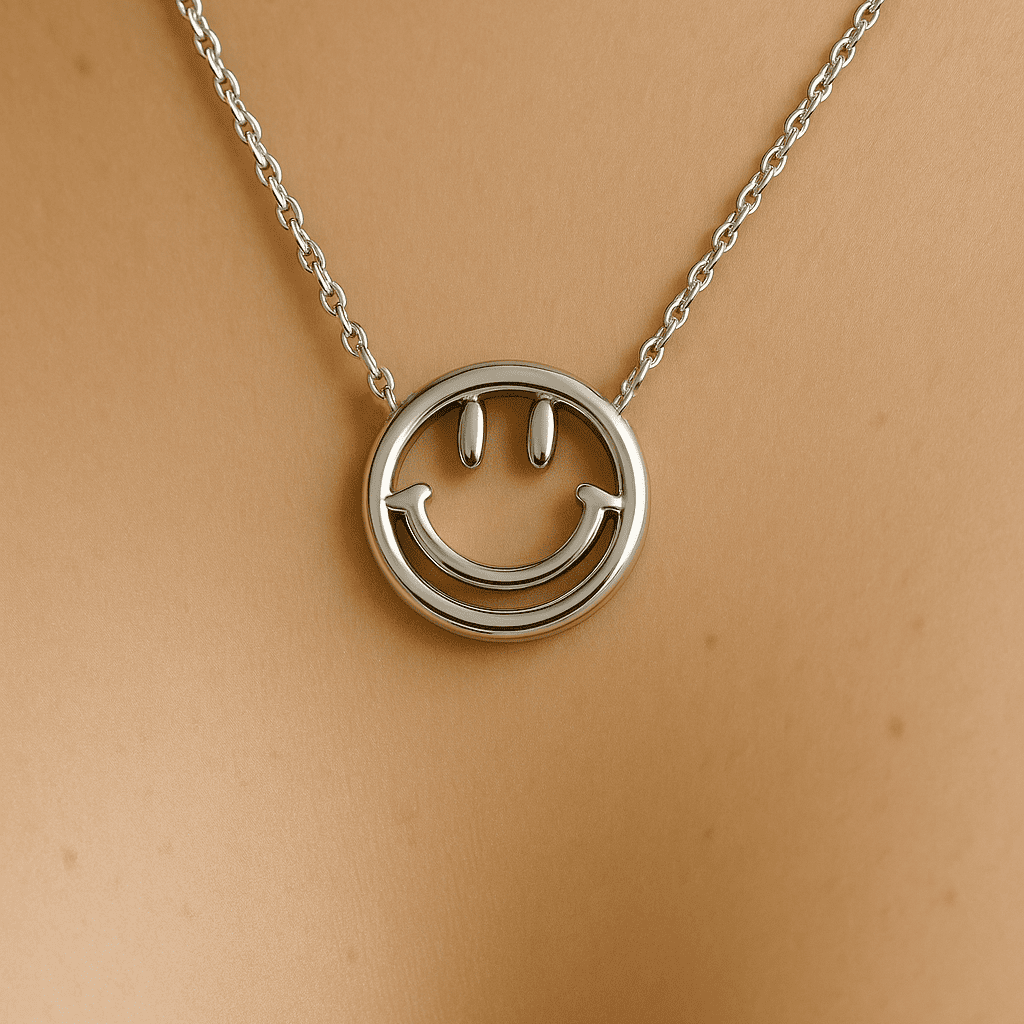 A minimalistic silver necklace with a smooth, high-polish smiley face pendant, worn on bare skin and captured in soft lighting with a luxury product photography aesthetic.